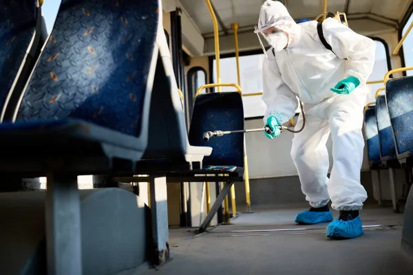 Pest control worker spraying inside a bus